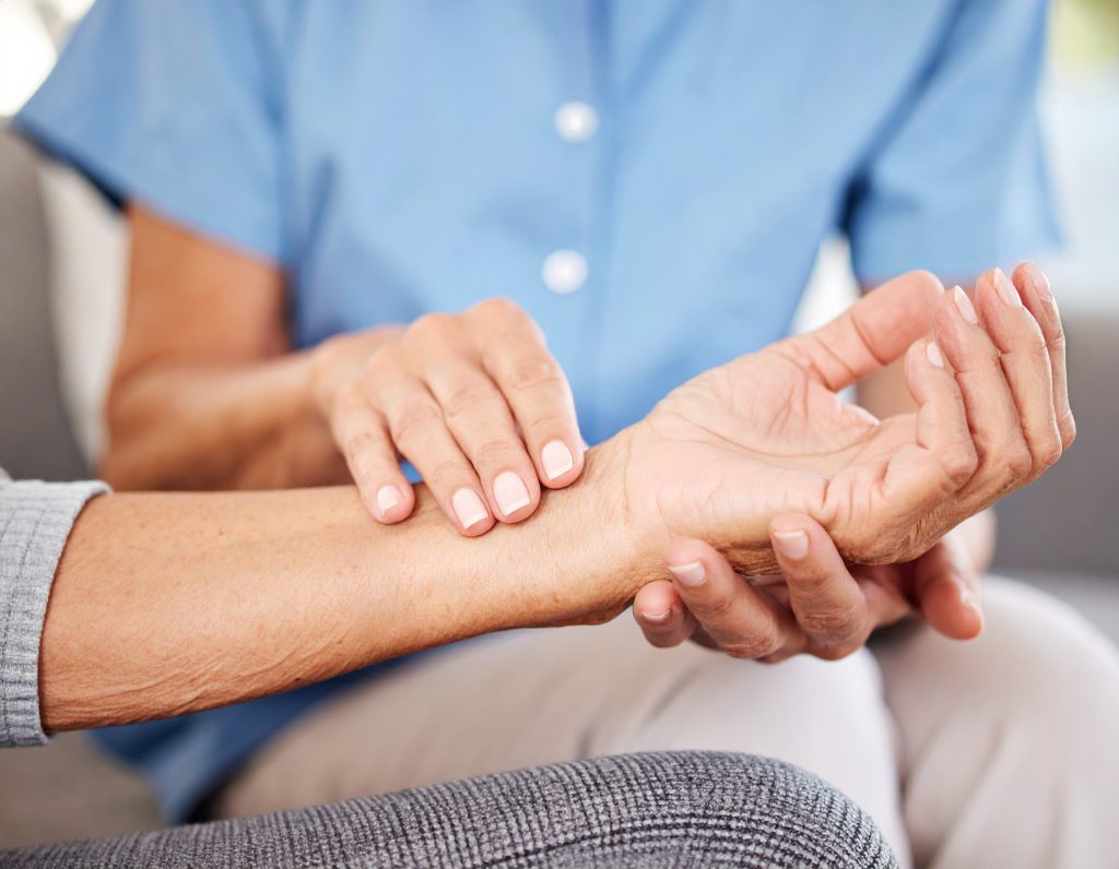 Eine Person in einer blauen Bluse misst Puls an einem Handgelenk