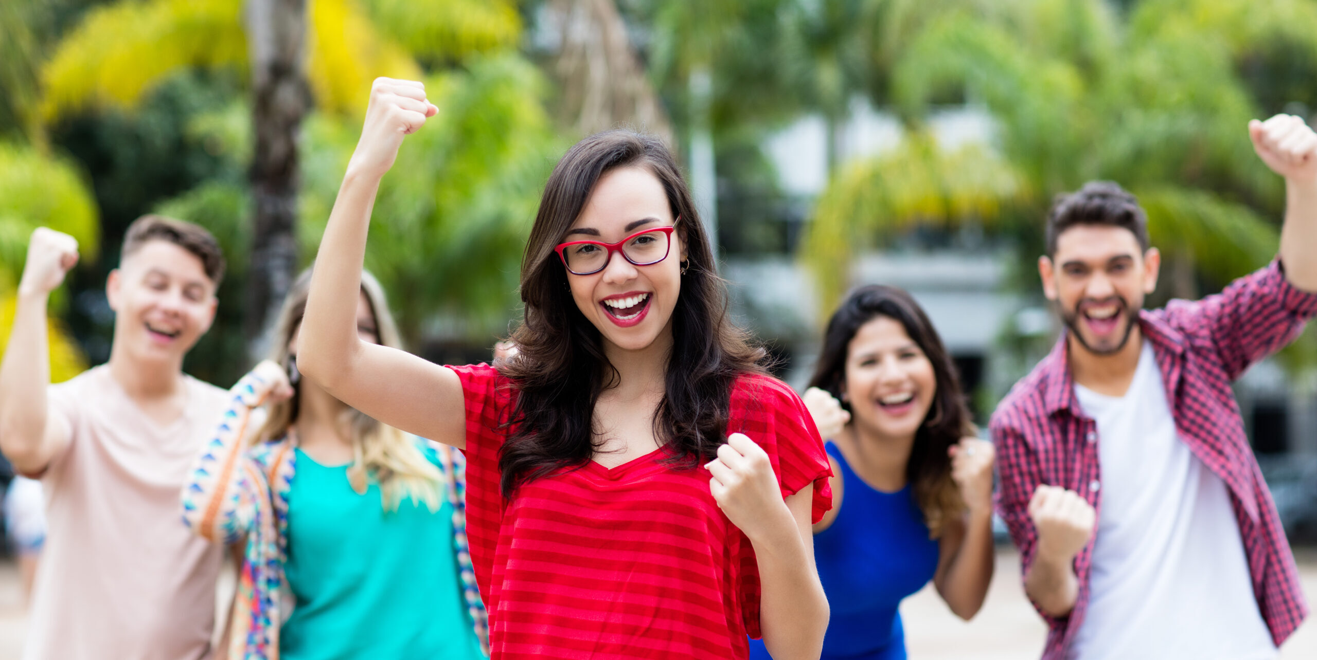 viele junge Menschen freuen sich und reißen die Arme nach oben