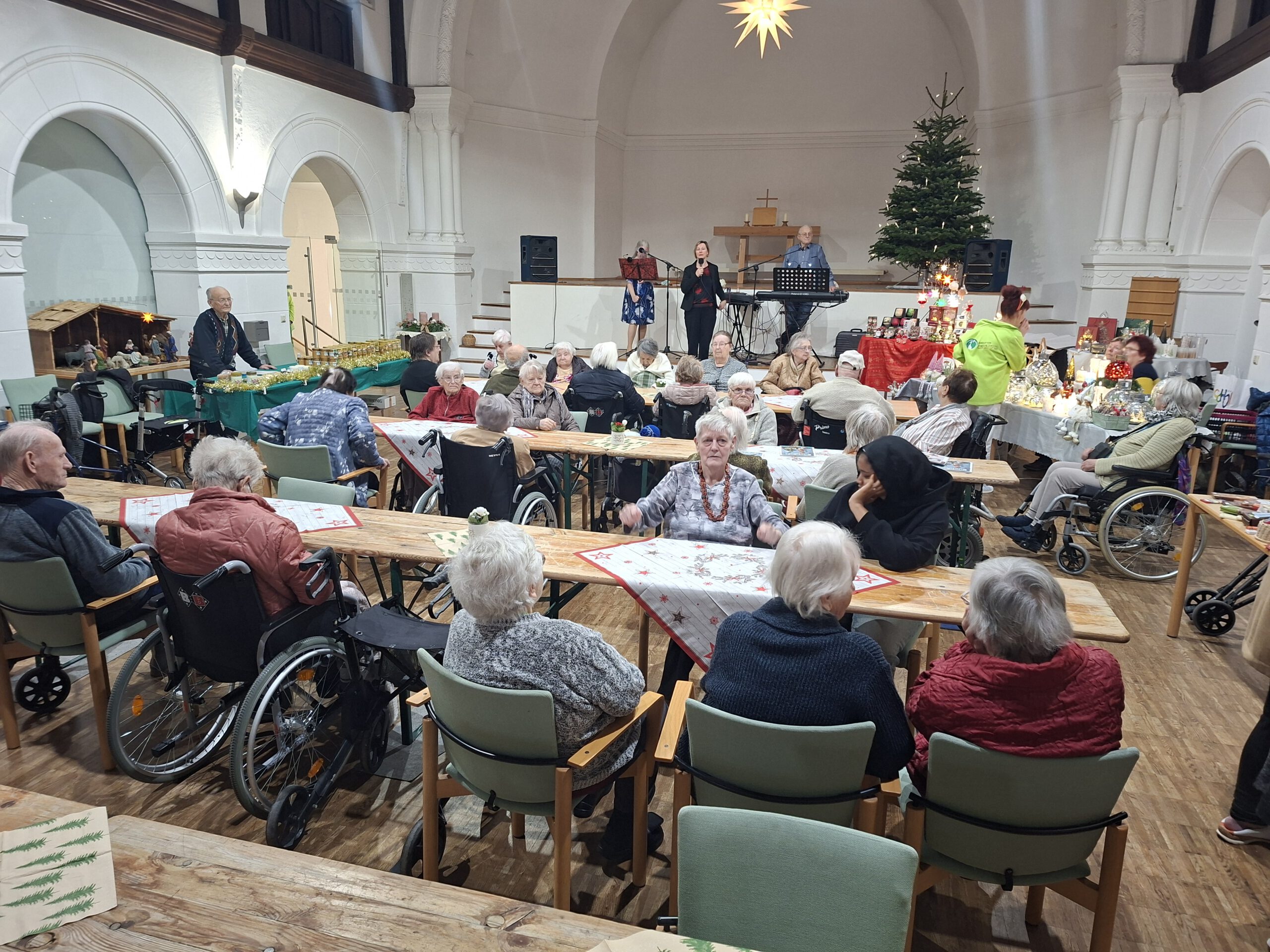 Die Bewohner und Gäste sitzen an langen Tischen und lauschen der Musik.