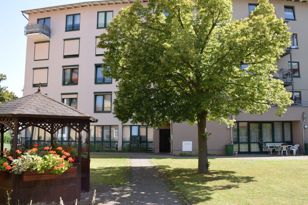 Blick auf das Haus des Altenpflegeheims mit Pavillon und großem Baum