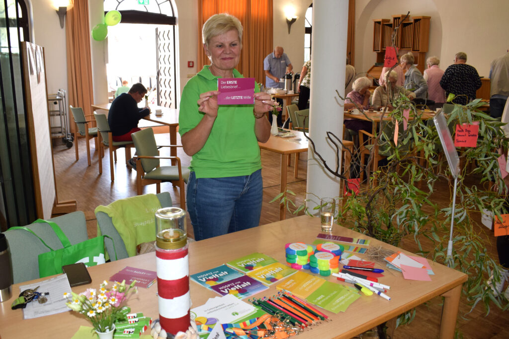 Berit Kuhn bei ihrer Arbeit als ehrenamtliche Mitarbeiterin an einem Stand des Hospizdienstes mit einer Karte in der Hand
