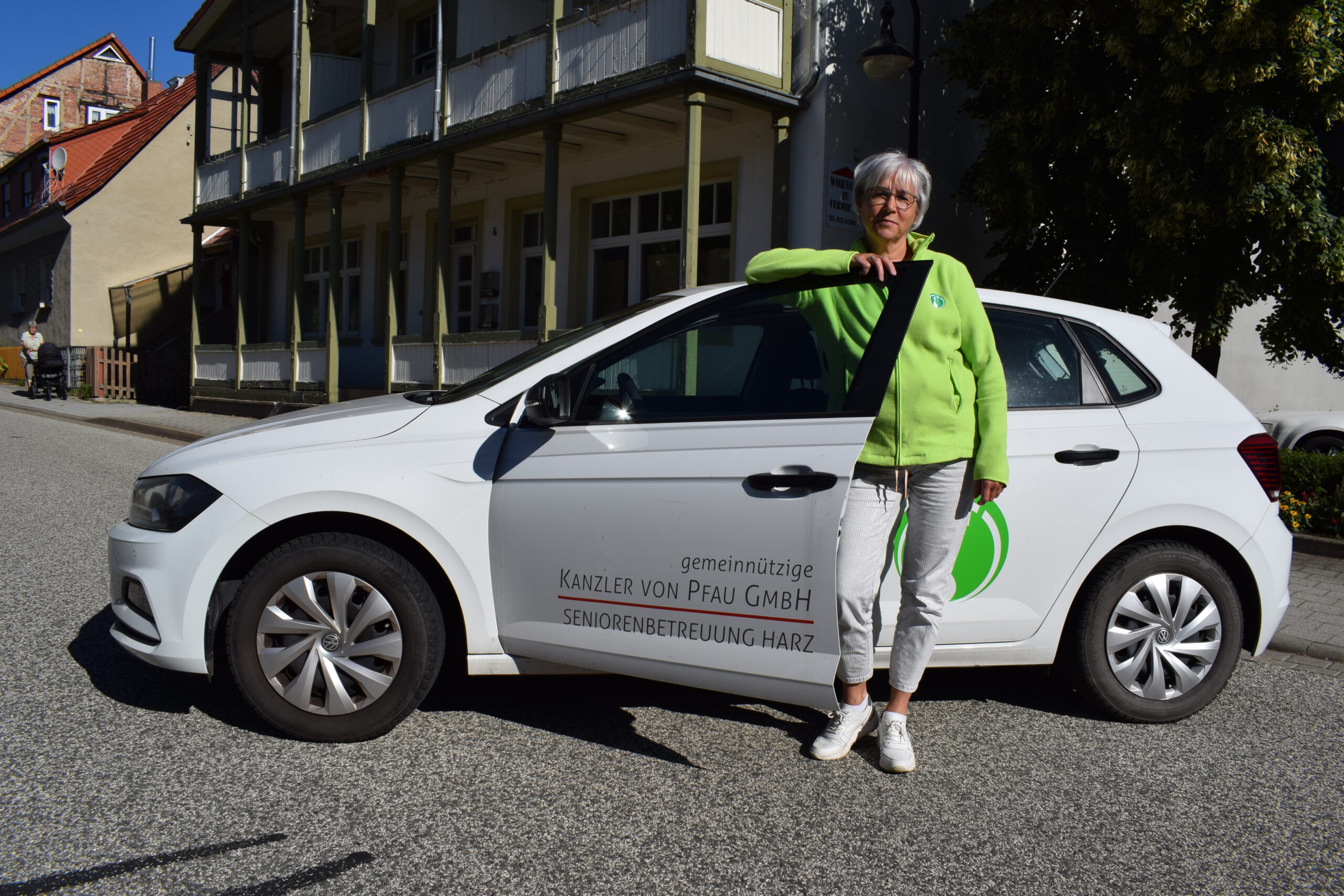 Eine Frau steht am Pflegedienstauto