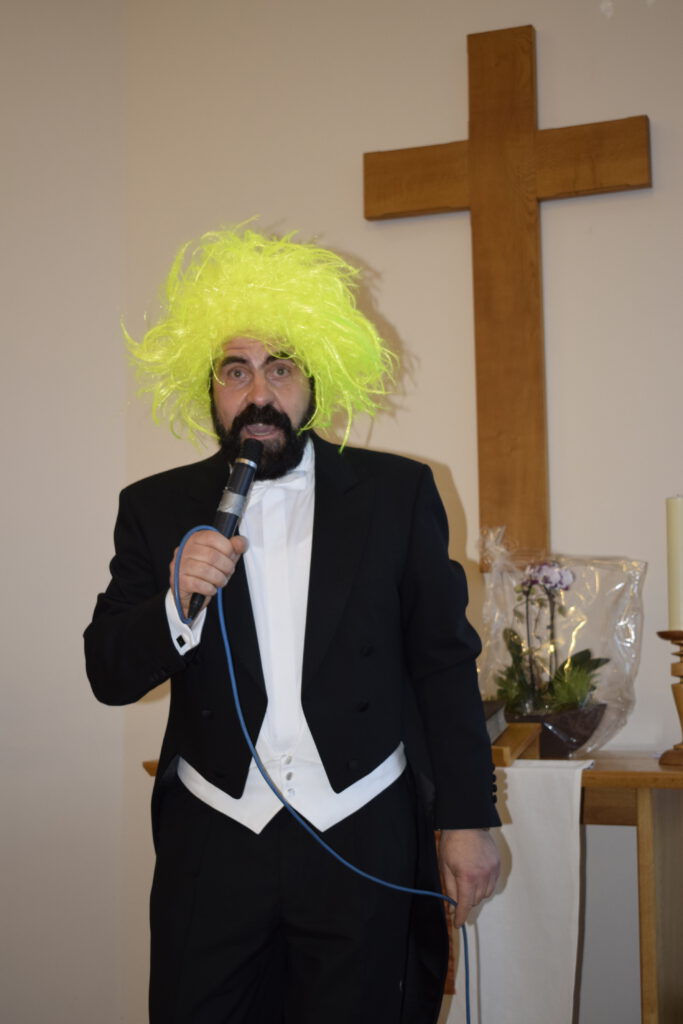 Ein Künstler mit gelber Struppelperücke singt das Lied "Was kann der Sigismund dafür, dass er so schön ist"