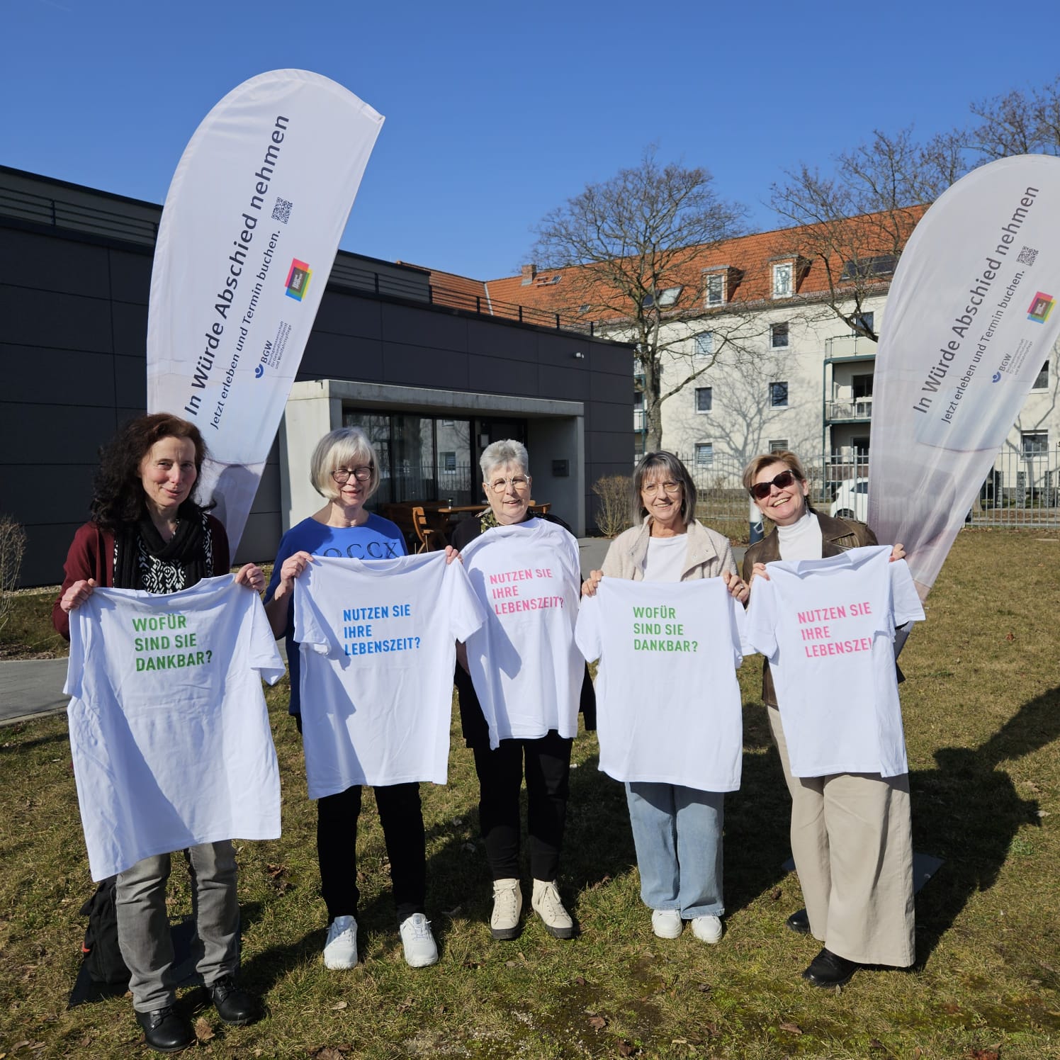Fünf Ehrenamtliche halten je ein T-Shirt nach vorn mit Sprüchen zu Dankbarkeit