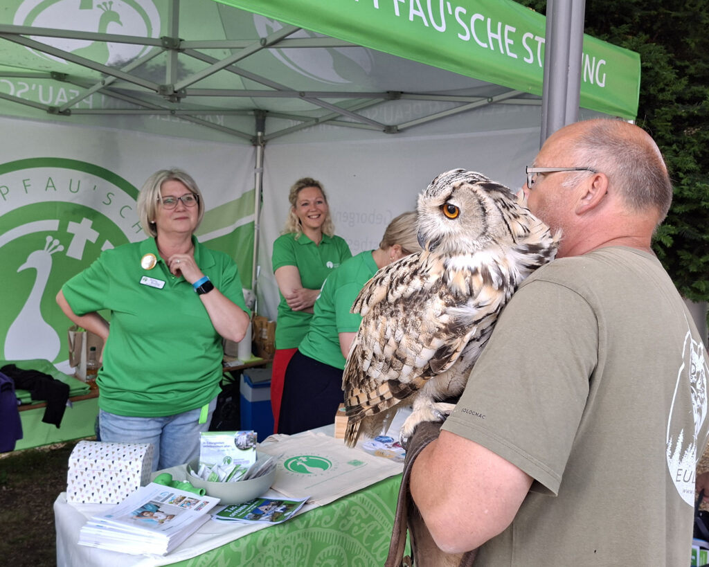 Mitarbeiter der Stiftung am Stand. Zu Gast ist eine Eule.